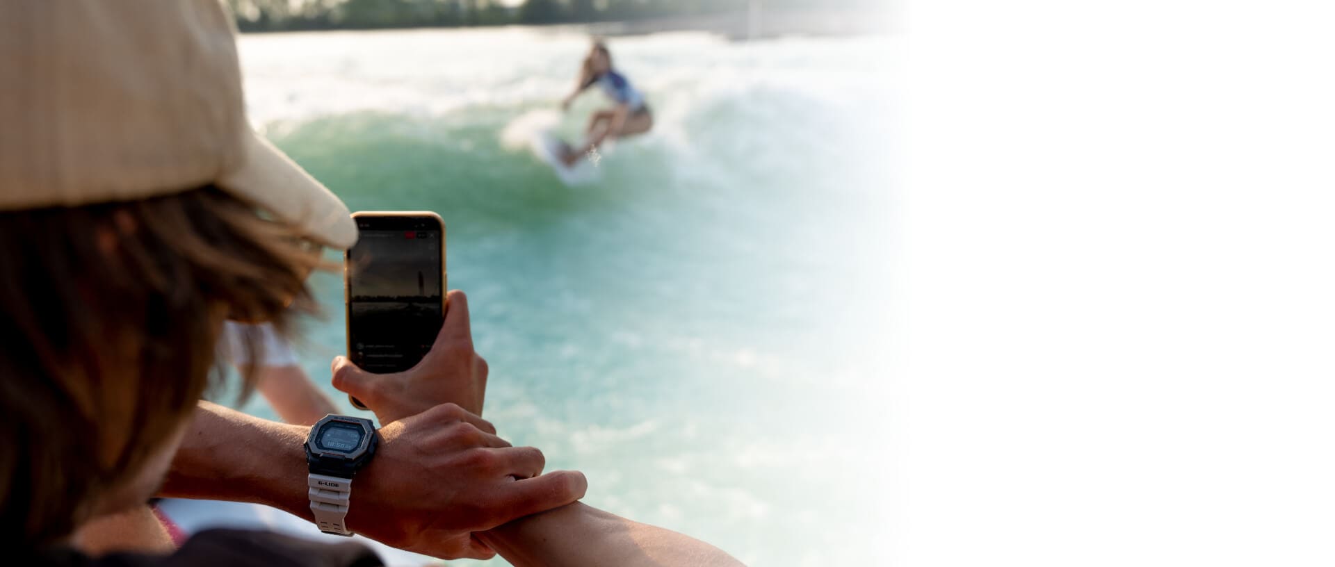 Una surfista es filmada por una persona desde su teléfono móvil. Esta persona lleva puesto el G-SHOCK G-LIDE con brazalete plateado.