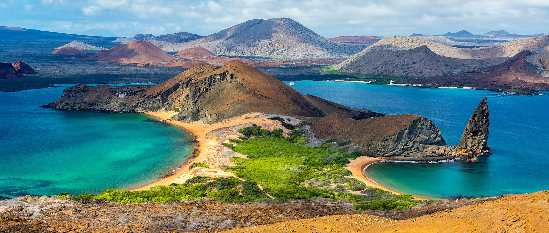 Un brazo de mar rodeado de un paisaje montañoso predominantemente árido, en cuyos valles el verde de los bosques brilla al sol.