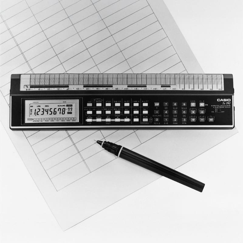 Black and white image of the ruler calculator on a sheet of paper next to a pen.