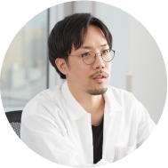 Portrait of product designer Shunsuke Oka with brown hair, round glasses and white shirt