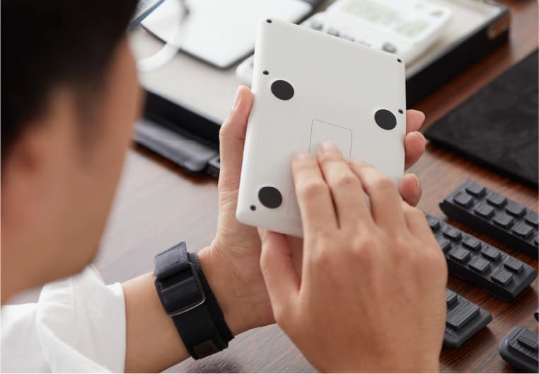 Product designer Oka holding the ergonomic calculator with the back facing upwards, rubber studs are attached to the back