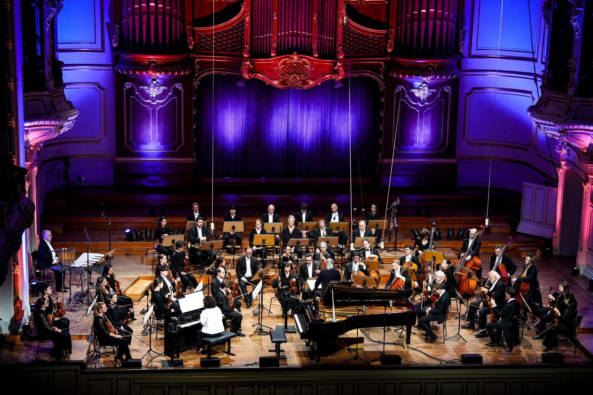 Akiko's piano, surrounded by a large symphony orchestra on a festive stage
