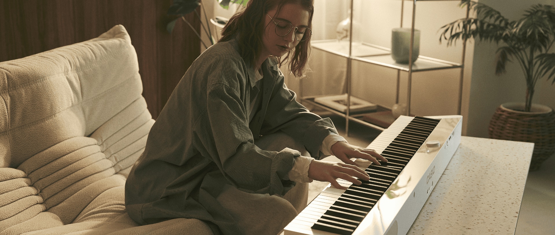 A young woman plays the PX-S1100MB on a table in the living room.