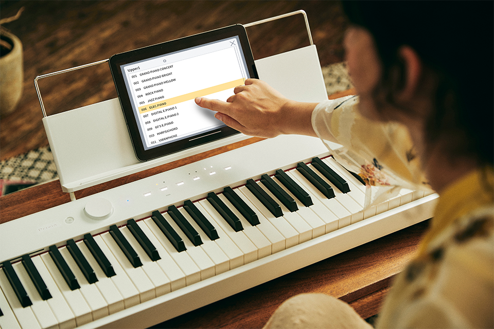 A woman sits at the keyboard and selects a song in the app.