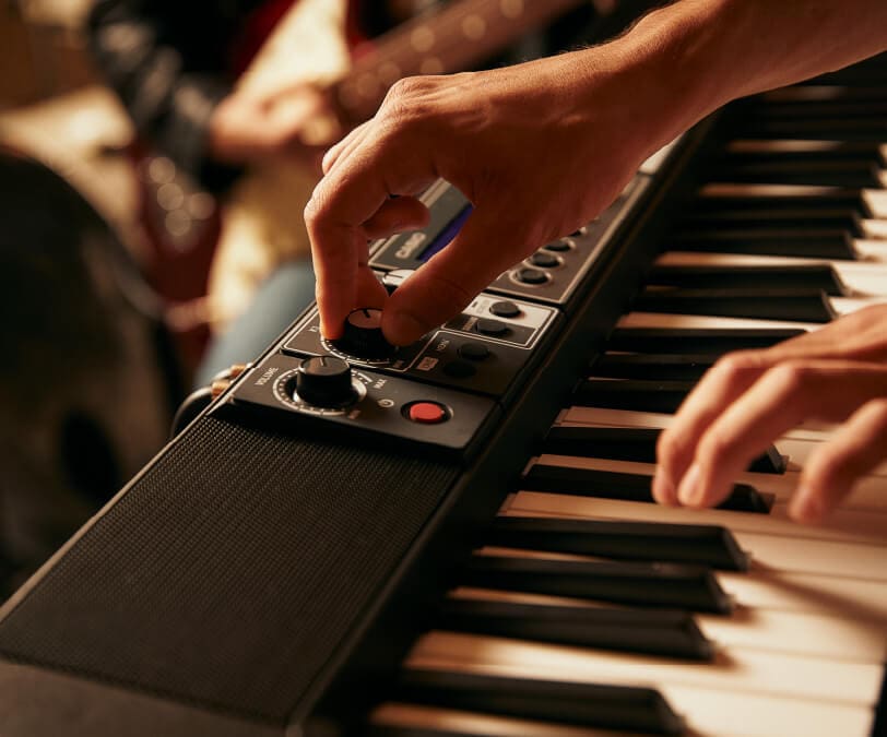 Close-up of the keyboard of the Casiotone CT-S500, with one hand touching a control on the panel and the other hand playing the digital piano