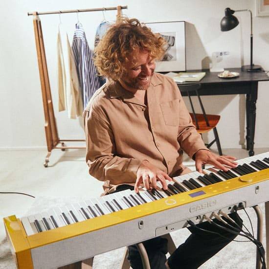 Benny Sings sits smiling at his PX-S7000 and plays the piano
