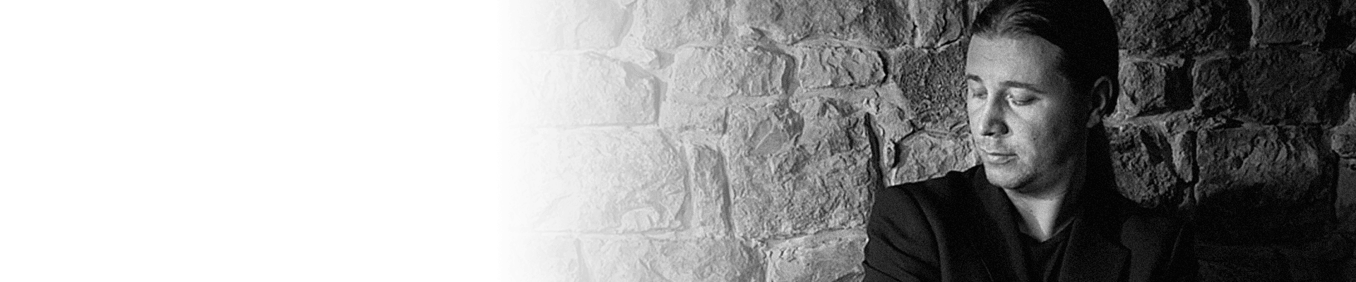 A black and white picture of Kristian Terzic sitting leaning against a wall.