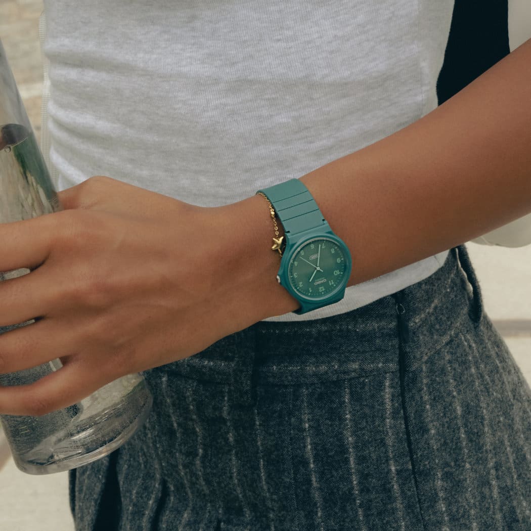 The green MQ-24B with analogue time display on the wrist of a woman holding a bottle of water