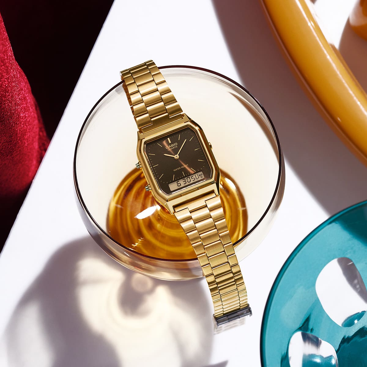 The gold-colored wristwatch AQ-230 with a brown-analog watchface on a coffeecup.