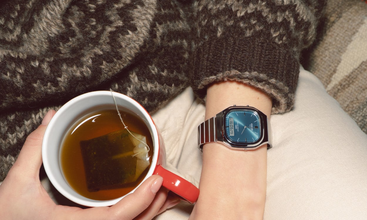 Close-up of a woman from above wearing the AQ-240E-3A and holding a cup of tea.