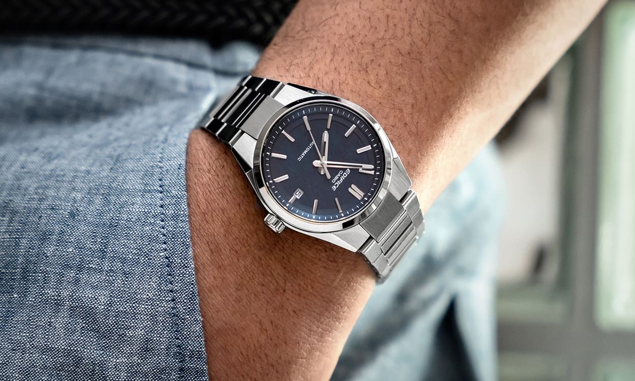 Close-up of the EFK-110 with a dark analogue dial on the wrist of a man putting his hand in his trouser pocket.