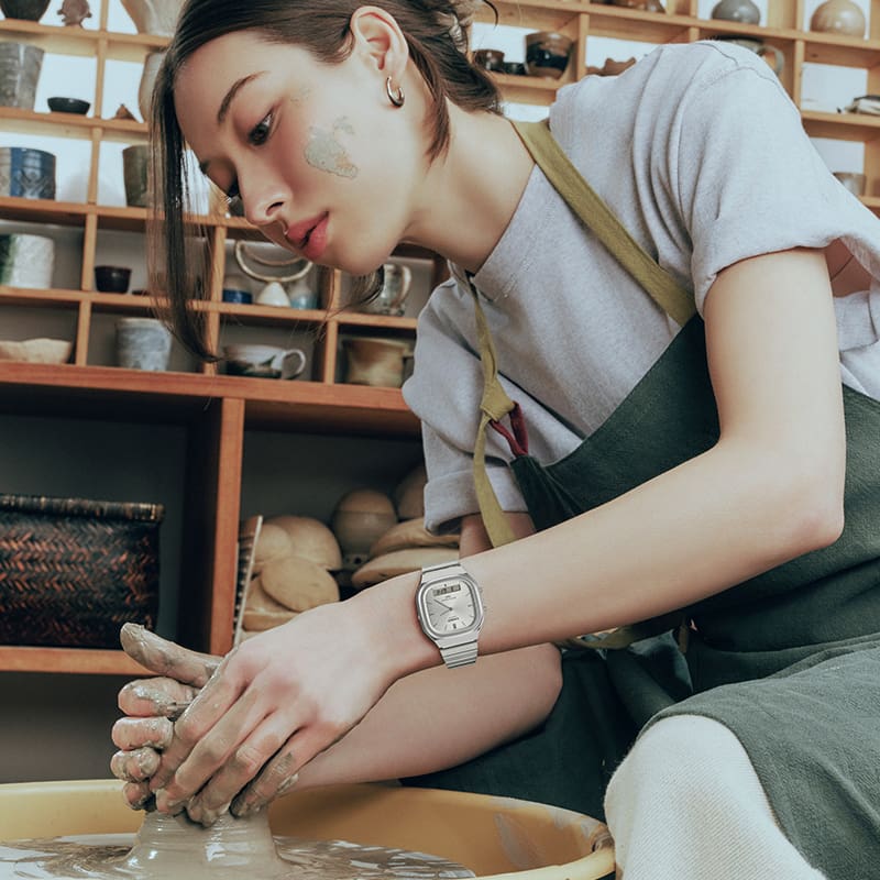 A ceramic artist working carefully on pottery in a studio wears the silver colored AQ-240E-7A analog watch.
