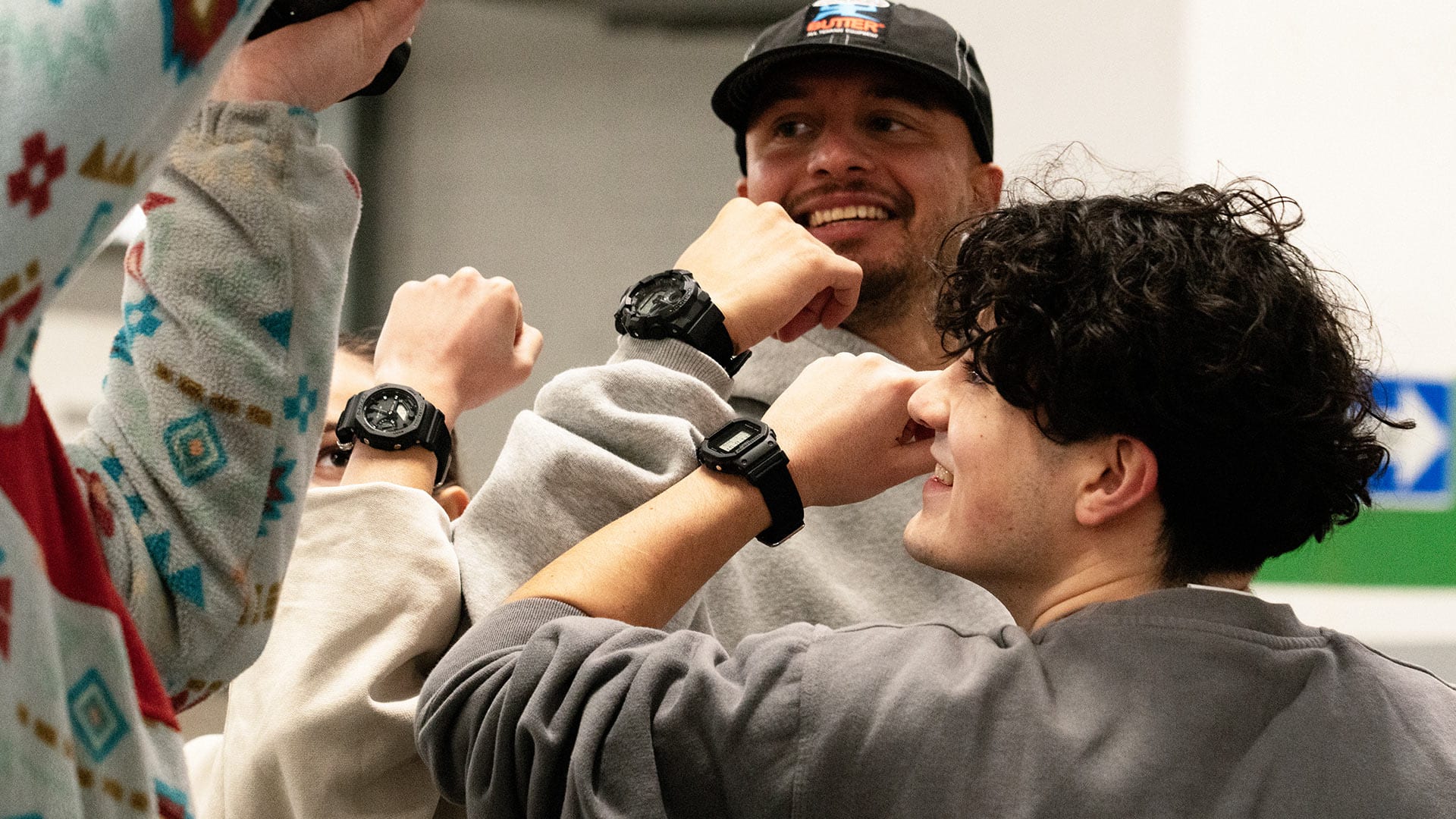 Three people wear the new Utility Black watches and show them to the photographer.