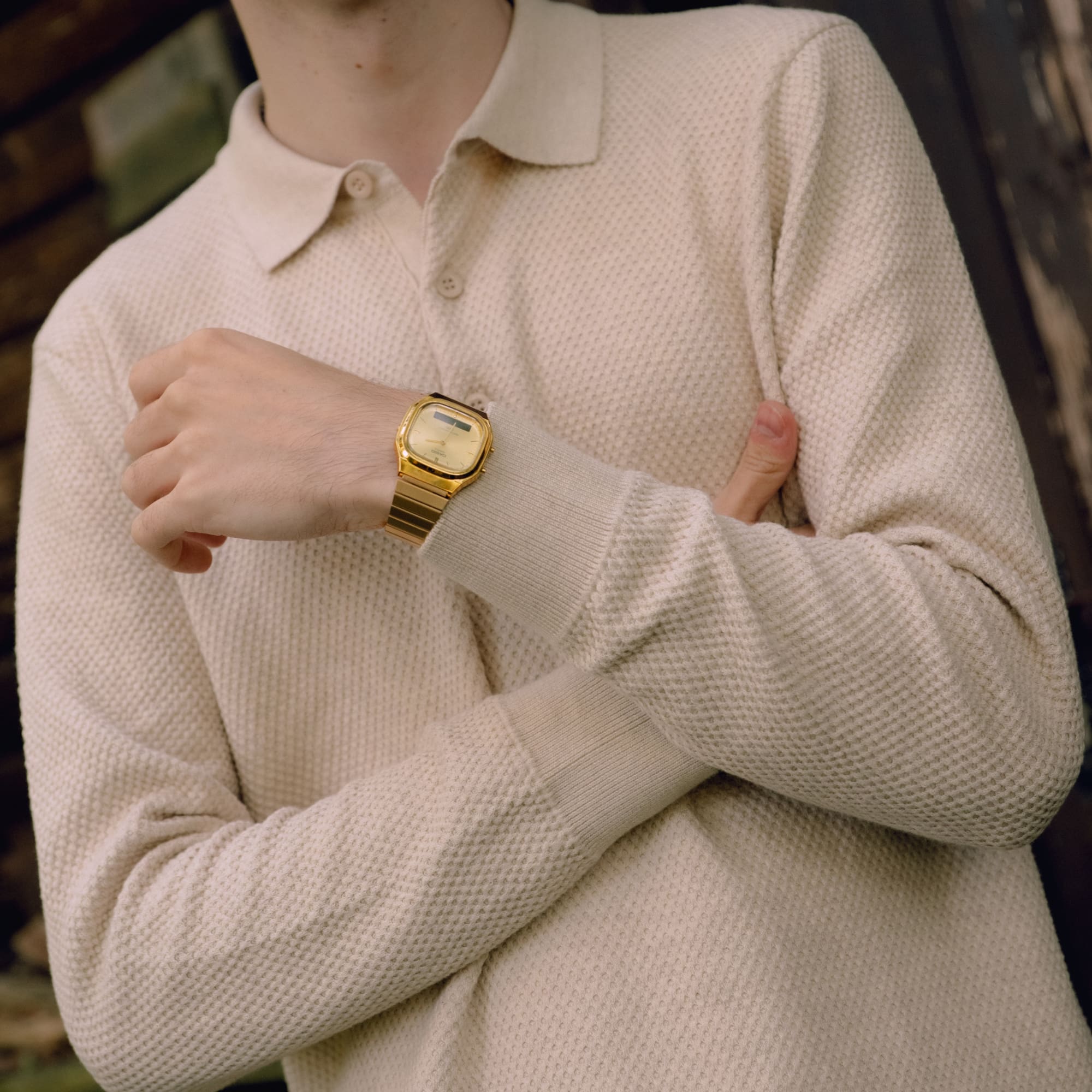 Un homme vêtu d'un pull beige porte la montre-bracelet AQ-240 en or au poignet.