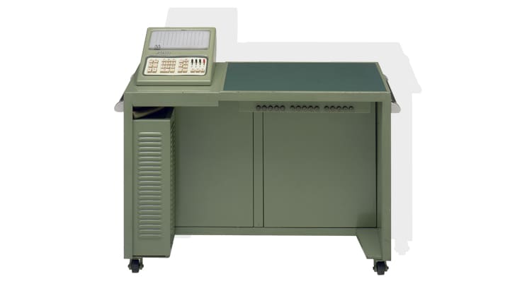 Un bureau vert olive sur lequel on peut voir un ordinateur CASIO.