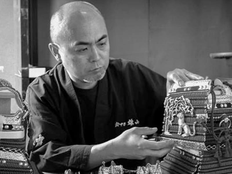 Susukine Yuzan tenant des pièces d'armure dans ses mains