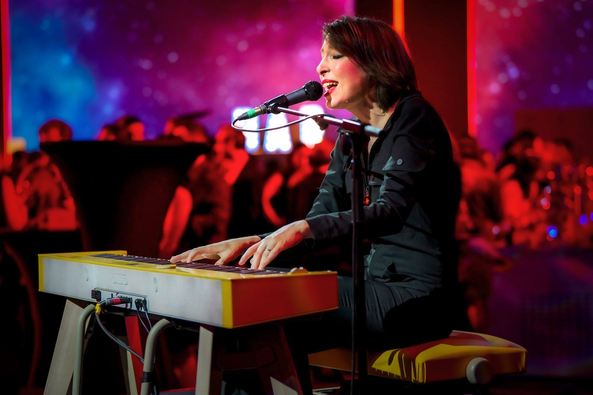 Une jeune femme chante et joue sur le piano numérique PRIVIA PX-S7000HM devant un public