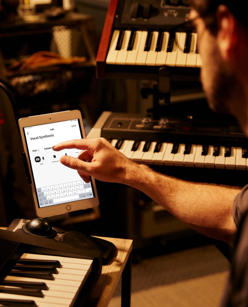 Un homme utilise l'application Vocal Synthesis sur une tablette placée à côté de son Casiotone CTS1000V