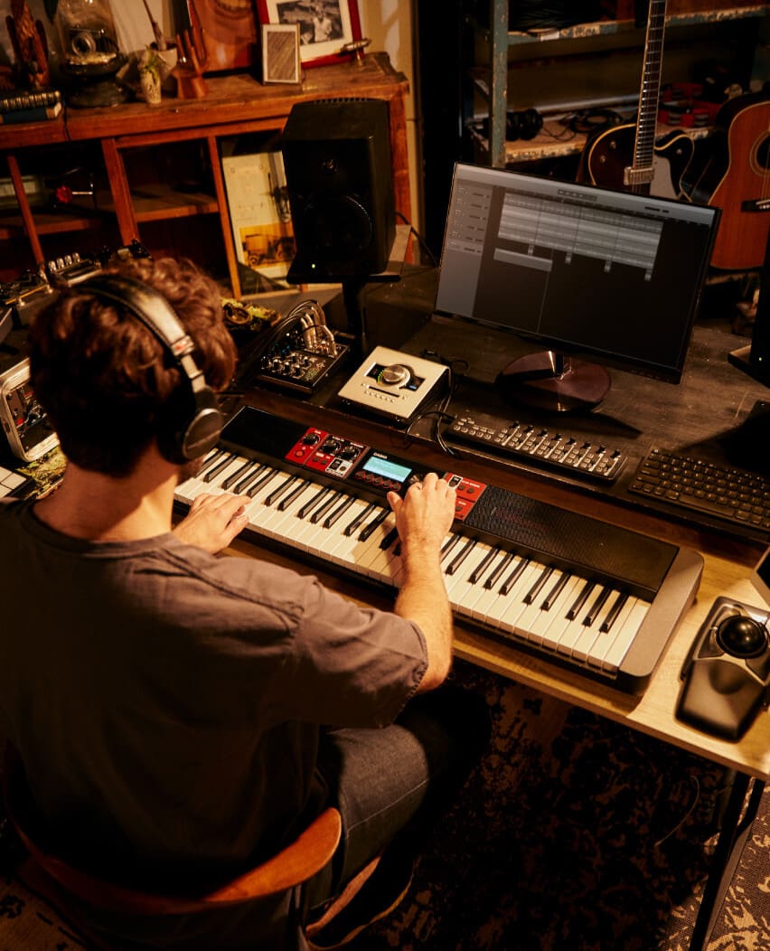 Un homme est assis devant un CTS1000V avec un casque, joue d'une main sur les touches et actionne les boutons de l'autre