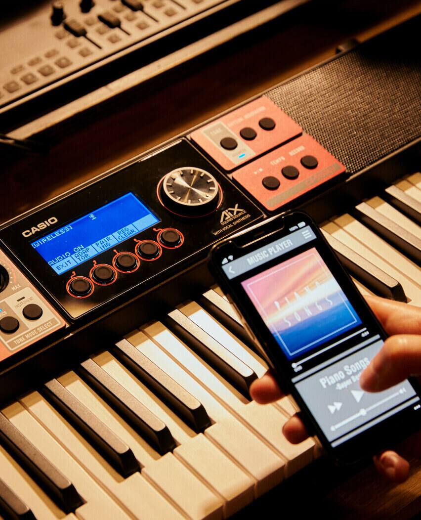Quelqu'un utilise le lecteur de musique sur son téléphone portable, qui est placé au-dessus des touches du clavier.
