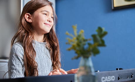 Une jeune fille joue en souriant sur le piano numérique Casiotone CT-S400