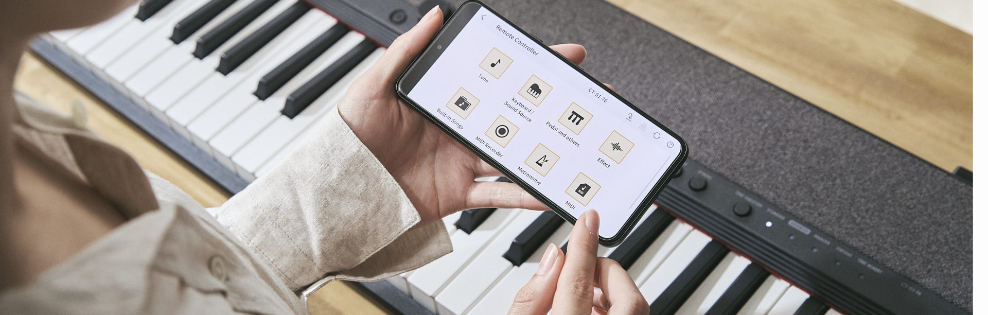 Une femme regarde son téléphone portable avec l'application CASIO MUSIC SPACE devant son clavier.