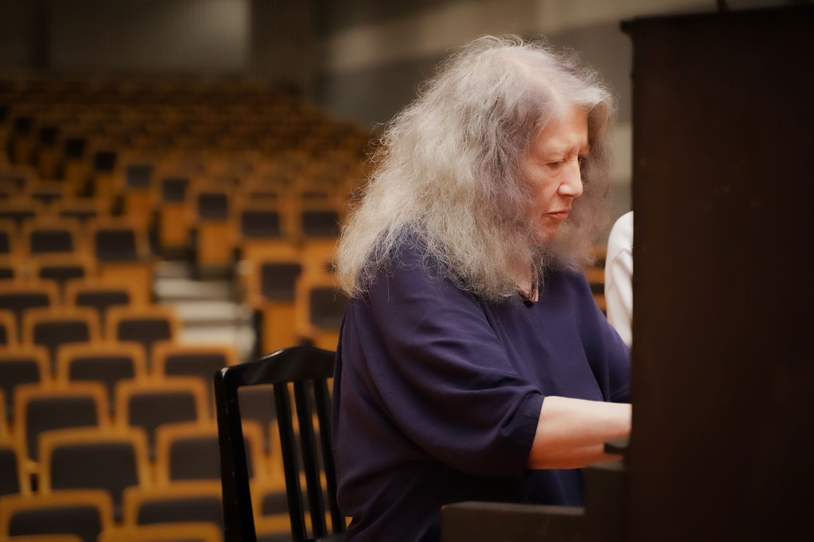 Martha Argerich est assise dans une salle et joue sur le piano d'Akiko.