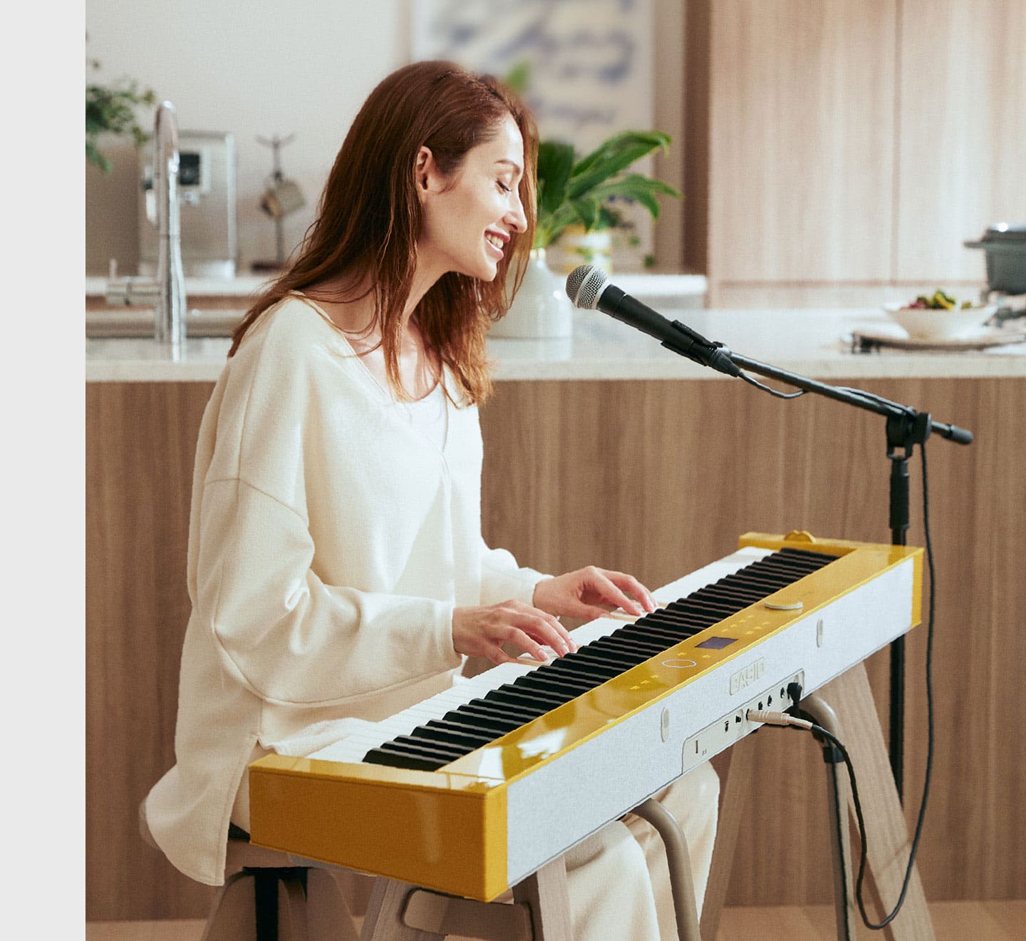 Une femme est assise devant le piano numérique PX-S7000HM, joue du piano et chante dans un micro.