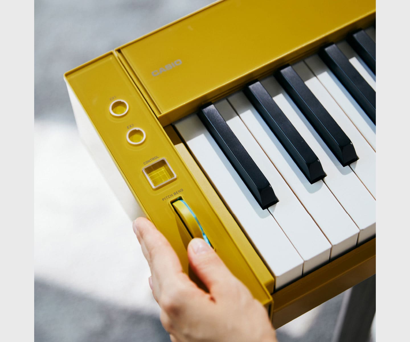 Gros plan sur les boutons rotatifs et les touches situés sur le côté gauche du piano numérique jaune PX-S6000.