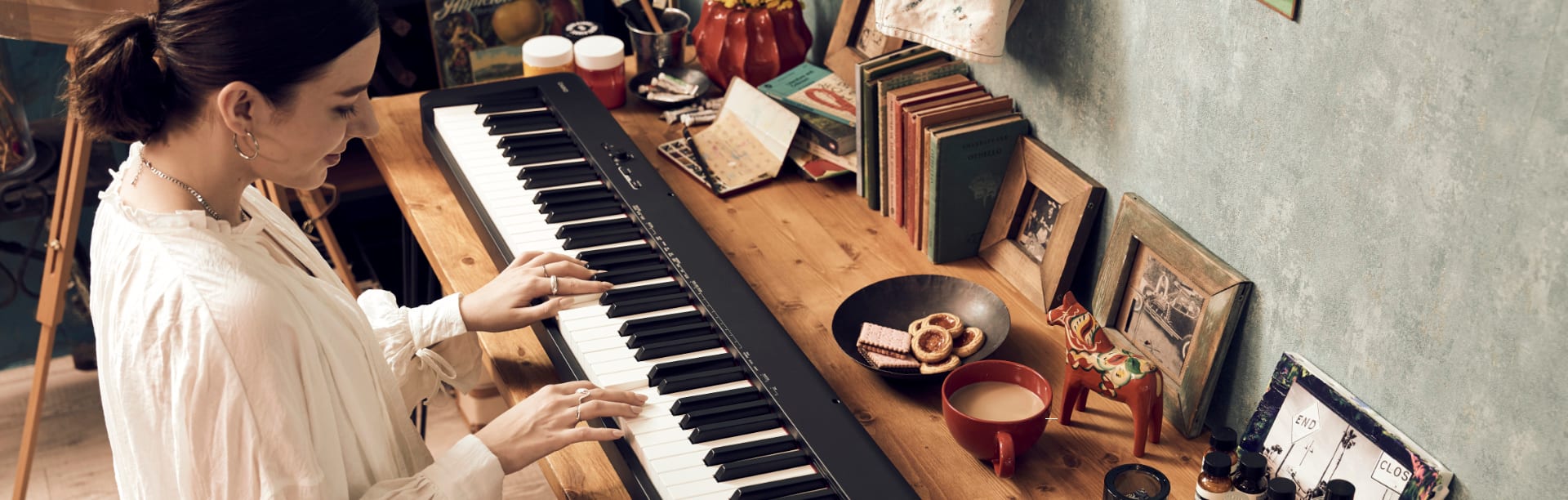 Une femme joue à son bureau sur le Casio Compact Piano CDP S100BK