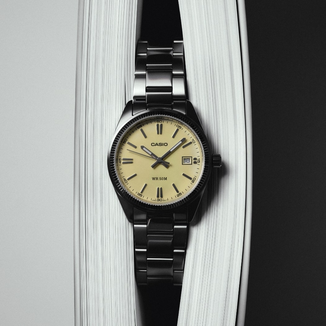Montre CASIO Timeless 1302 à cadran jaune et bracelet en acier, photographiée sur un fond blanc.