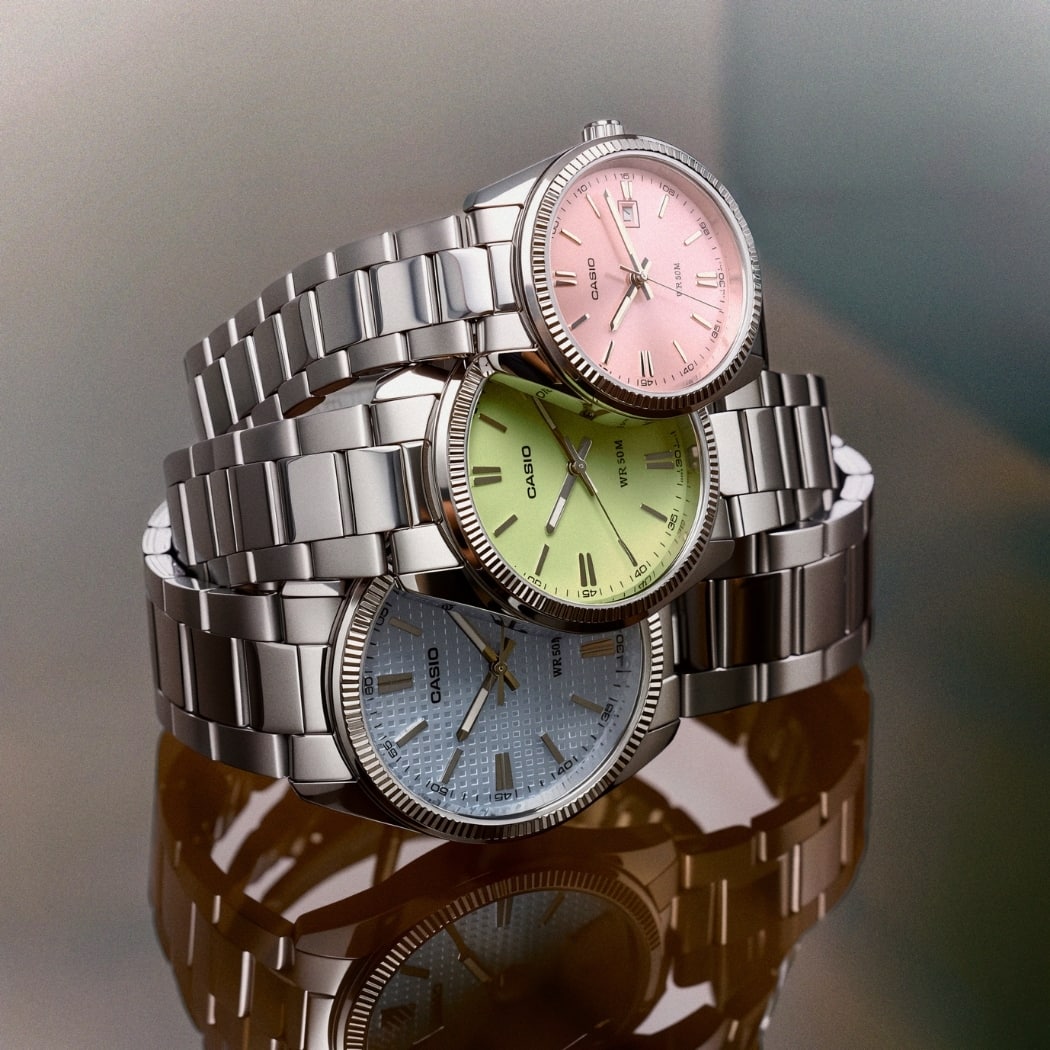 Trois montres CASIO Timeless UTP-1302 aux cadrans rose, vert et bleu empilées les unes sur les autres.