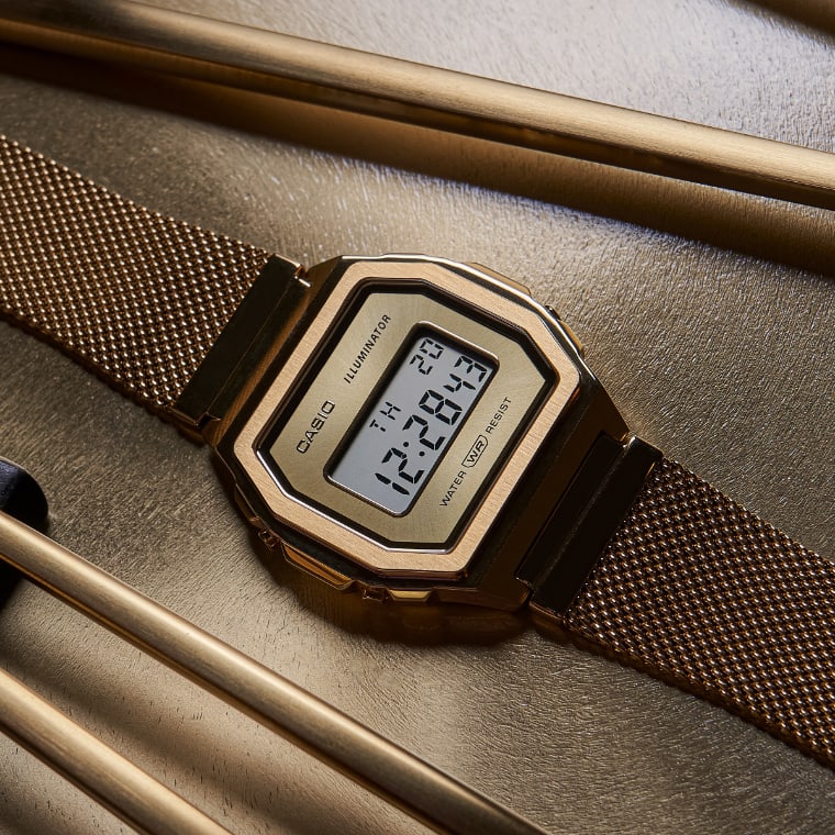 Une montre-bracelet en or de la collection Premium de CASIO Vintage est posée sur une table à côté de baguettes.