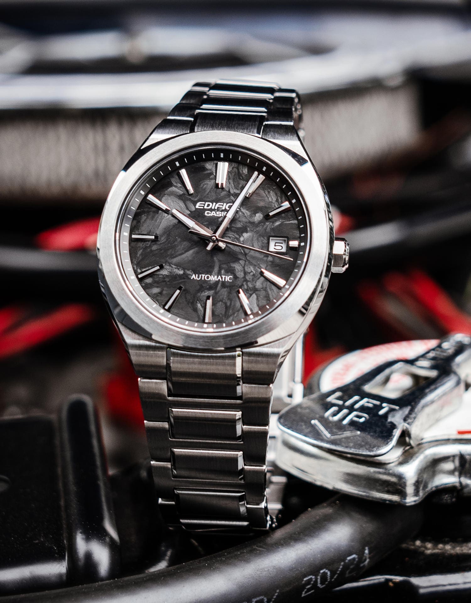Gros plan sur la montre automatique EFK-200CD-1A au cadran noir, posée à côté d'un porte-clés.