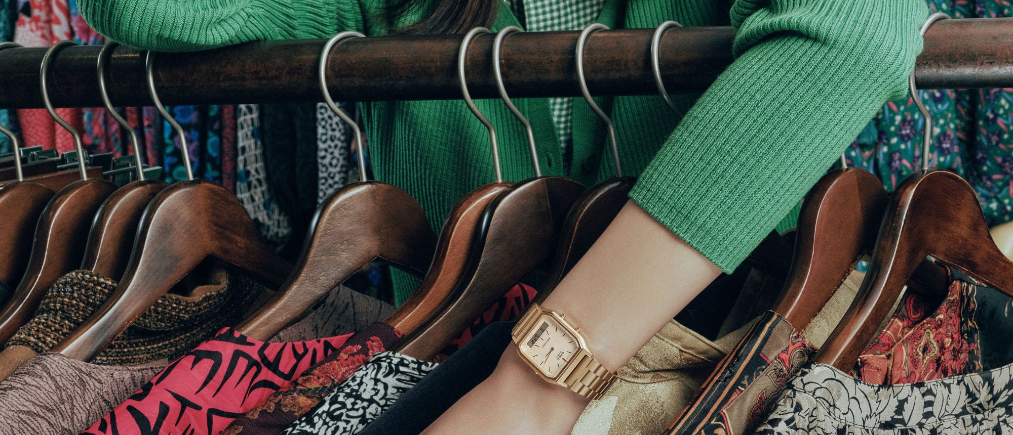 Une femme choisit des vêtements dans un magasin vintage. Elle porte la montre AQ-230A-7AMQY dorée.