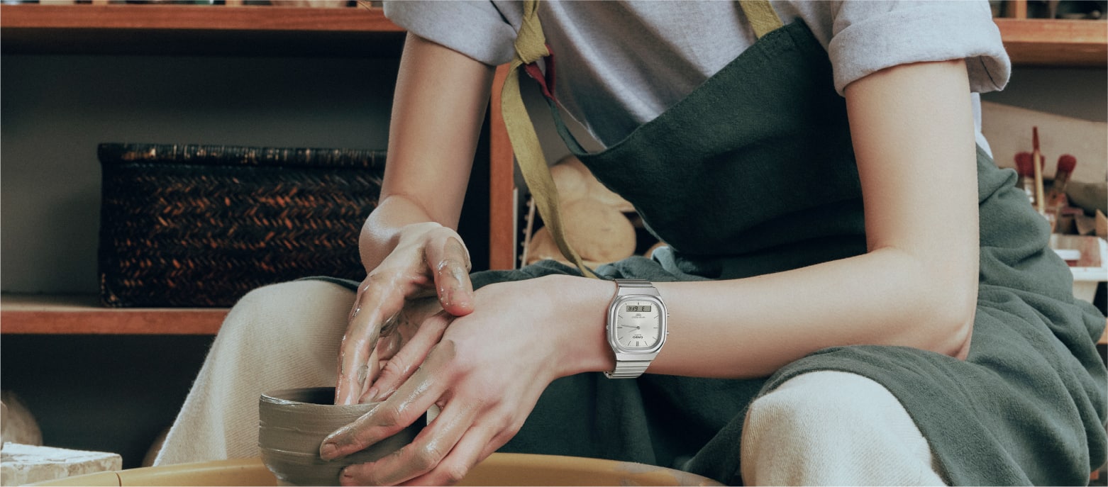 Une femme façonne de l'argile. Elle porte l’AQ-240E-7A, une montre analogique au bracelet argenté issue de la CASIO Vintage Collection.