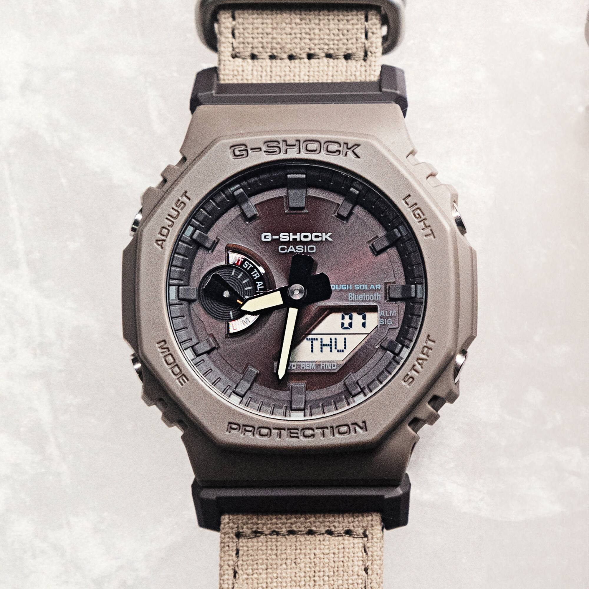 La montre hybride G-Shock Natural Coexist GA-B2100CT-5A avec bracelet en tissu vert-gris. L'image renvoie vers la page du produit.