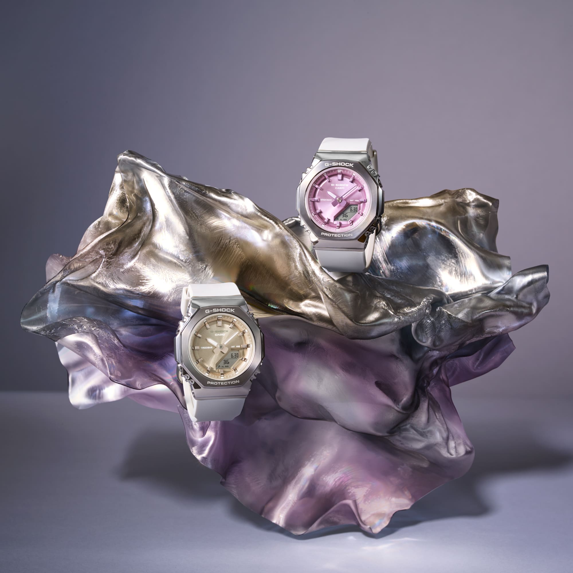 Les montres hybrides G-Shock Classic GM-S2110-7A9 et GM-S2110-7A6 avec bracelet blanc et cadrans colorés. L'image renvoie vers la GM-S2110-7A6 avec cadran rose métallisé.