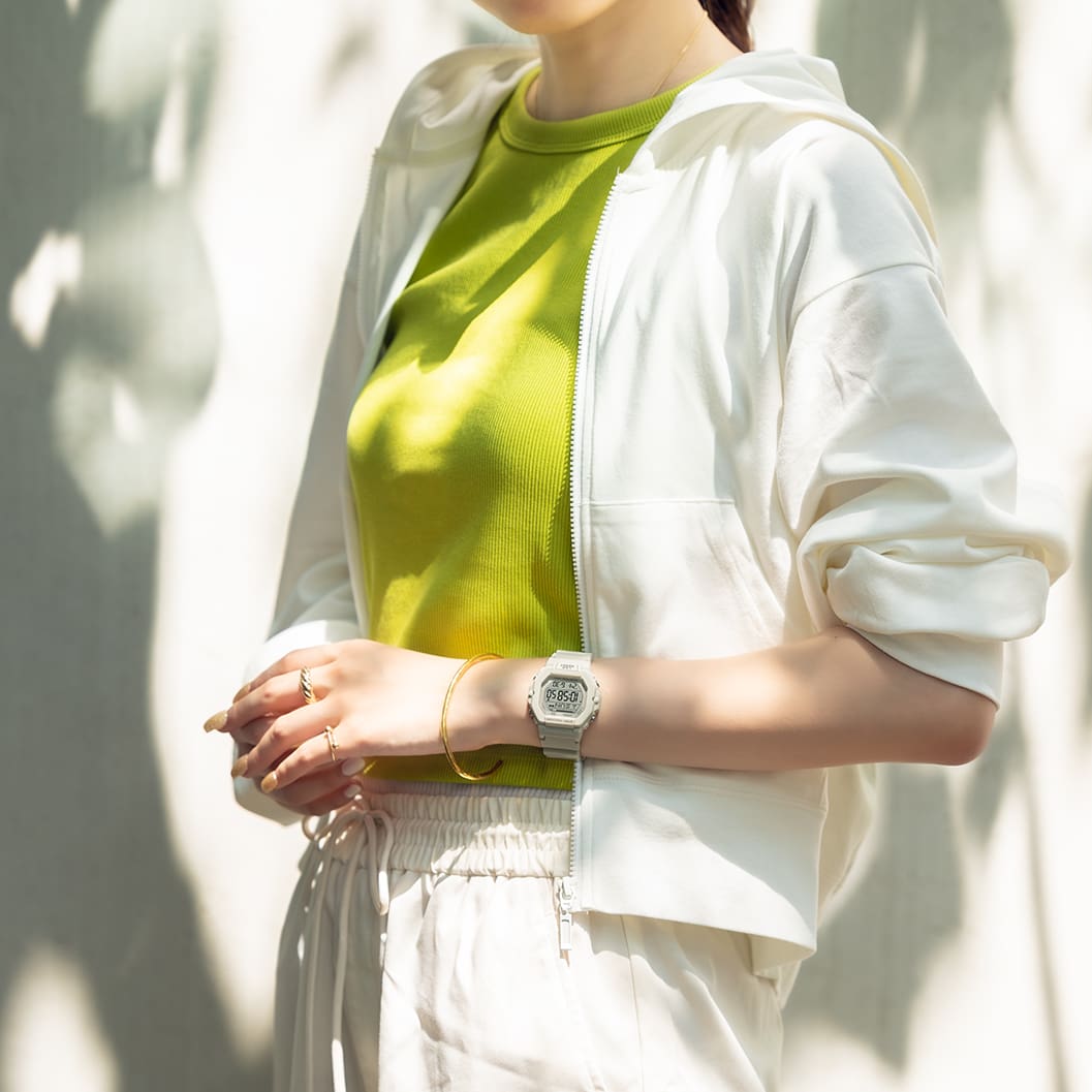 Une femme porte des vêtements de sport clairs et la montre-bracelet numérique de CASIO Collection en beige. L'heure est facile à lire grâce aux chiffres sombres.