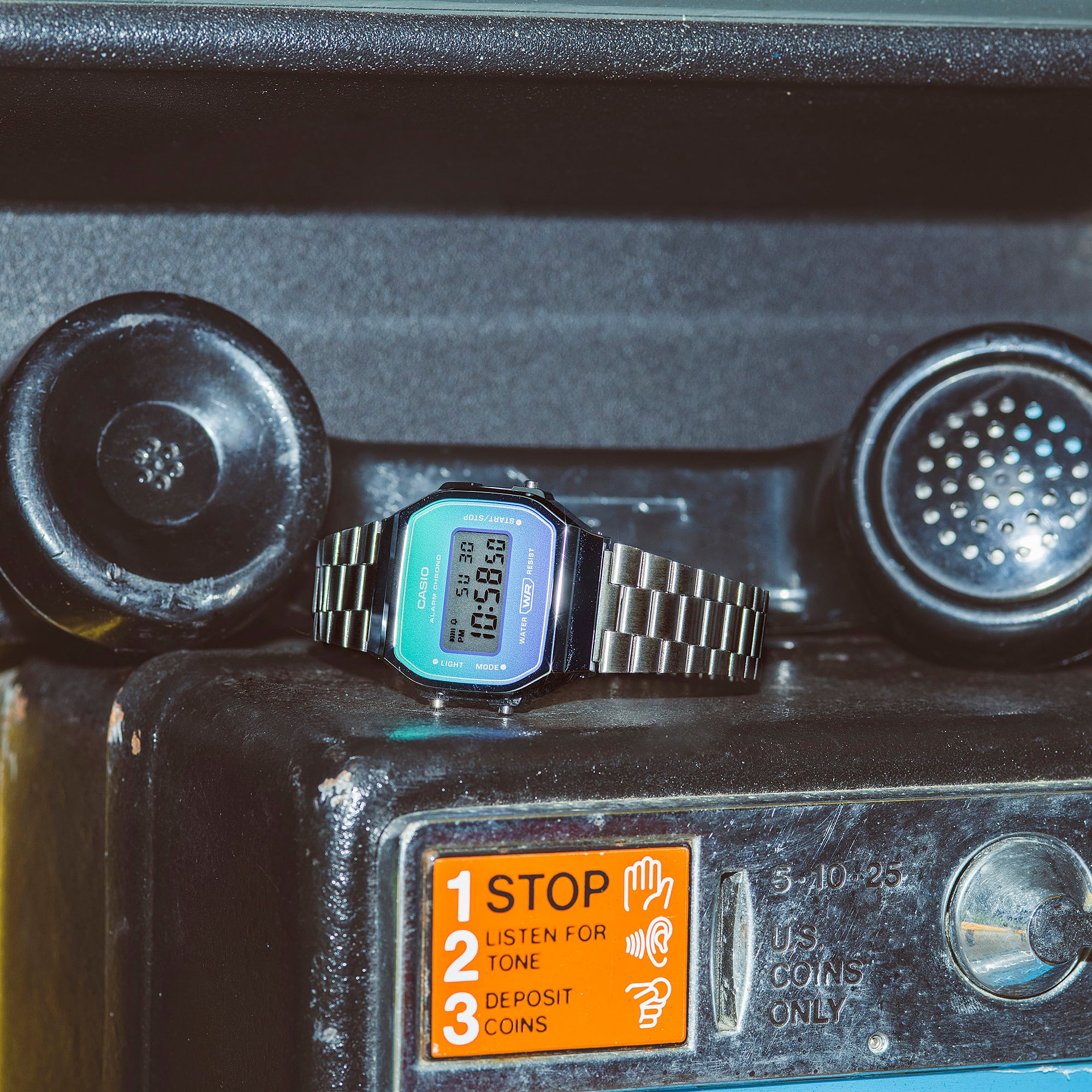 Montre numérique vintage Casio A168WER-2A avec bracelet argenté et dégradé turquoise-violet en dehors de l'affichage numérique de la montre.