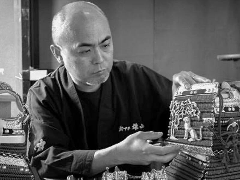 Susukine Yuzan con in mano alcune parti di un'armatura