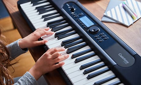 Primo piano delle mani che suonano la tastiera del pianoforte digitale Casiotone CT-S400