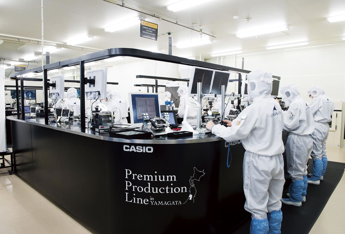 Uno sguardo dietro le quinte della linea di produzione premium a Yamagata, dove diverse persone sono sedute fianco a fianco davanti ai computer.
