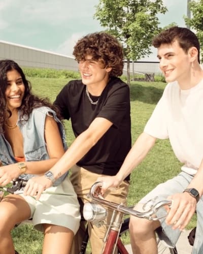 Tre persone attraversano un parco in bicicletta sotto il sole, indossando diversi modelli di Casio Vintage A168.