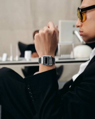 Un uomo è seduto a una scrivania e porta al polso il Casio Vintage A100WE-7BEF in argento.