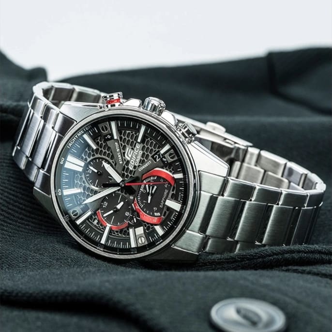 EQB-1200D-1A in argento con quadrante nero appoggiato su un cardigan nero