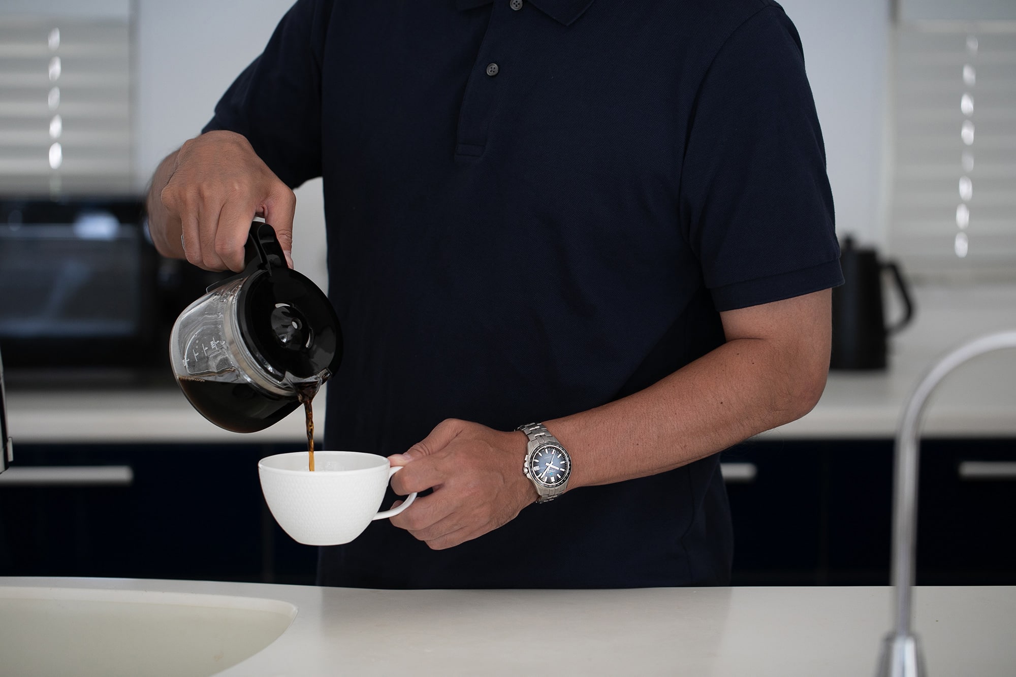 コーヒーを淹れている男性　左手に時計