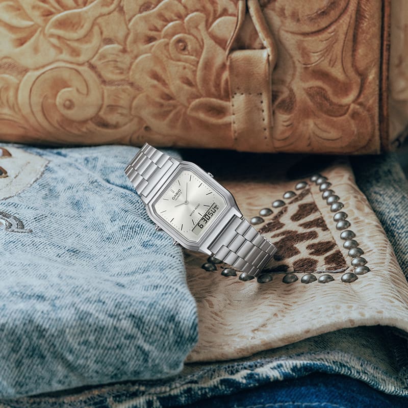 This is a photo of the G-SHOCK AQ-230A-7AMQY placed on textured fabrics and clothing items.