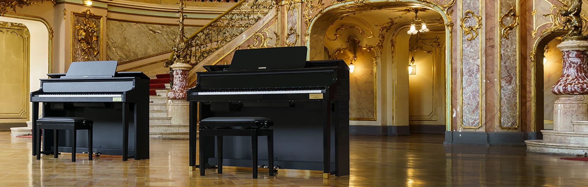 Wide angled front view of Celviano GP-310 and GP-510 Grand Hybrid pianos in lobby of ornate concert hall