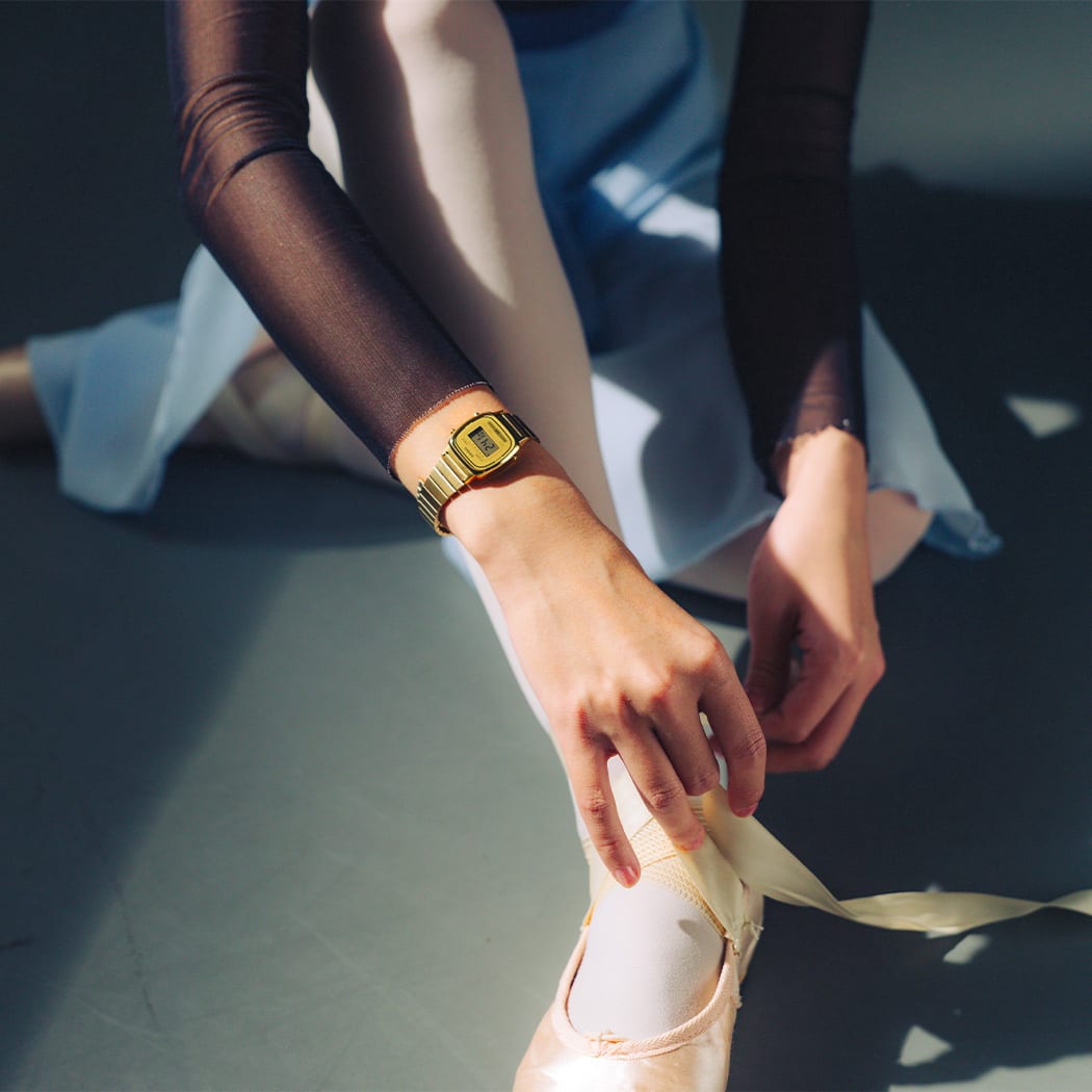 Primer plano de la muñeca de la bailarina de ballet que usa el pequeño LA670WG-9 de color dorado con pantalla digital.